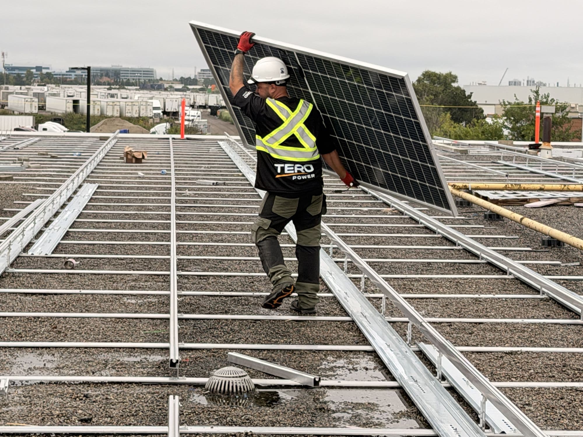 Tero Power installer carrying a module across ballasted rooftop racking