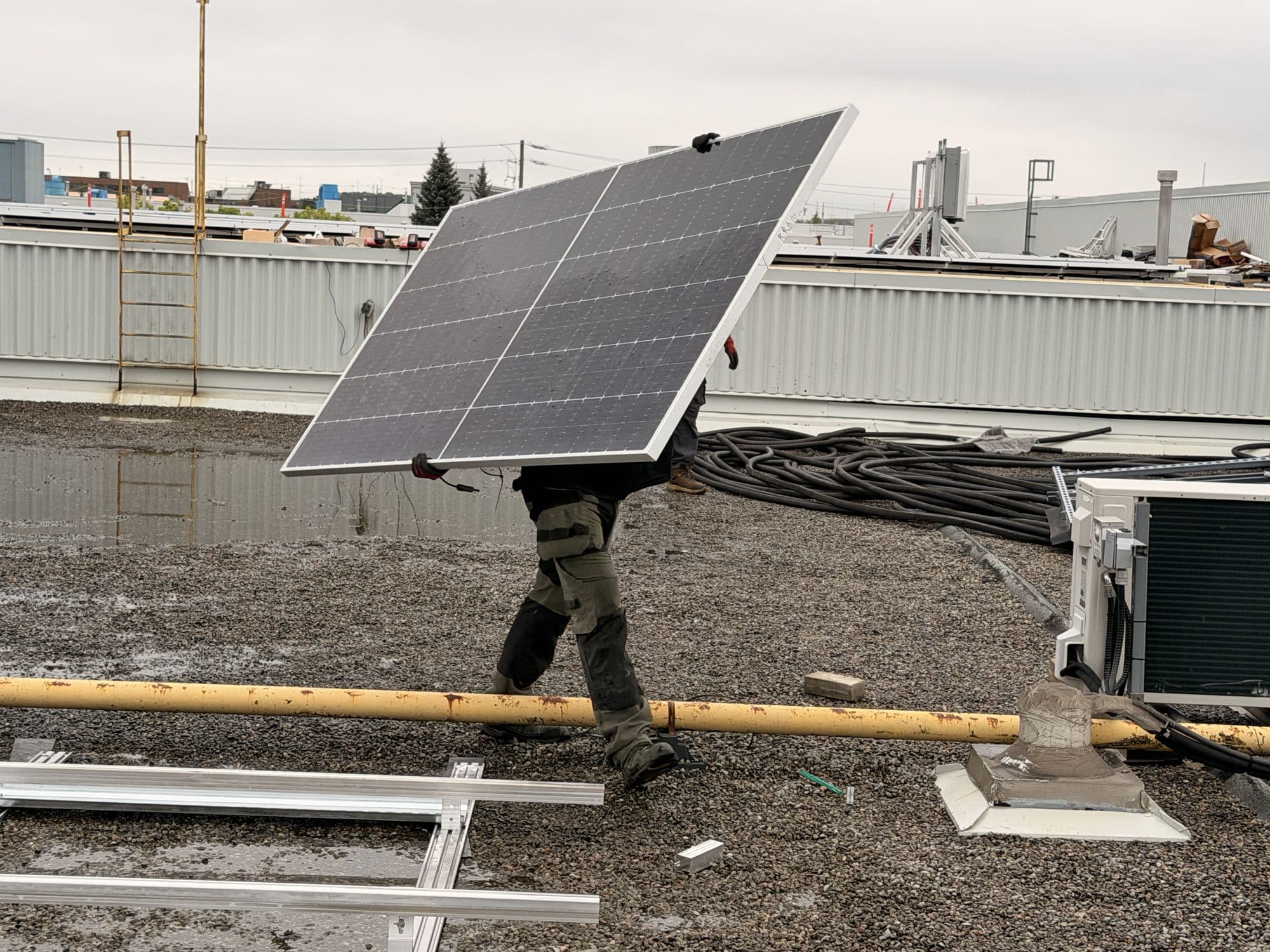 Tero Power installer carrying a solar module across rooftop racking
