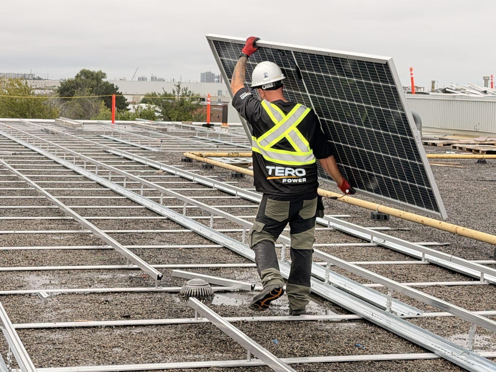 Tero Power installer carrying a solar module across the racking grid
